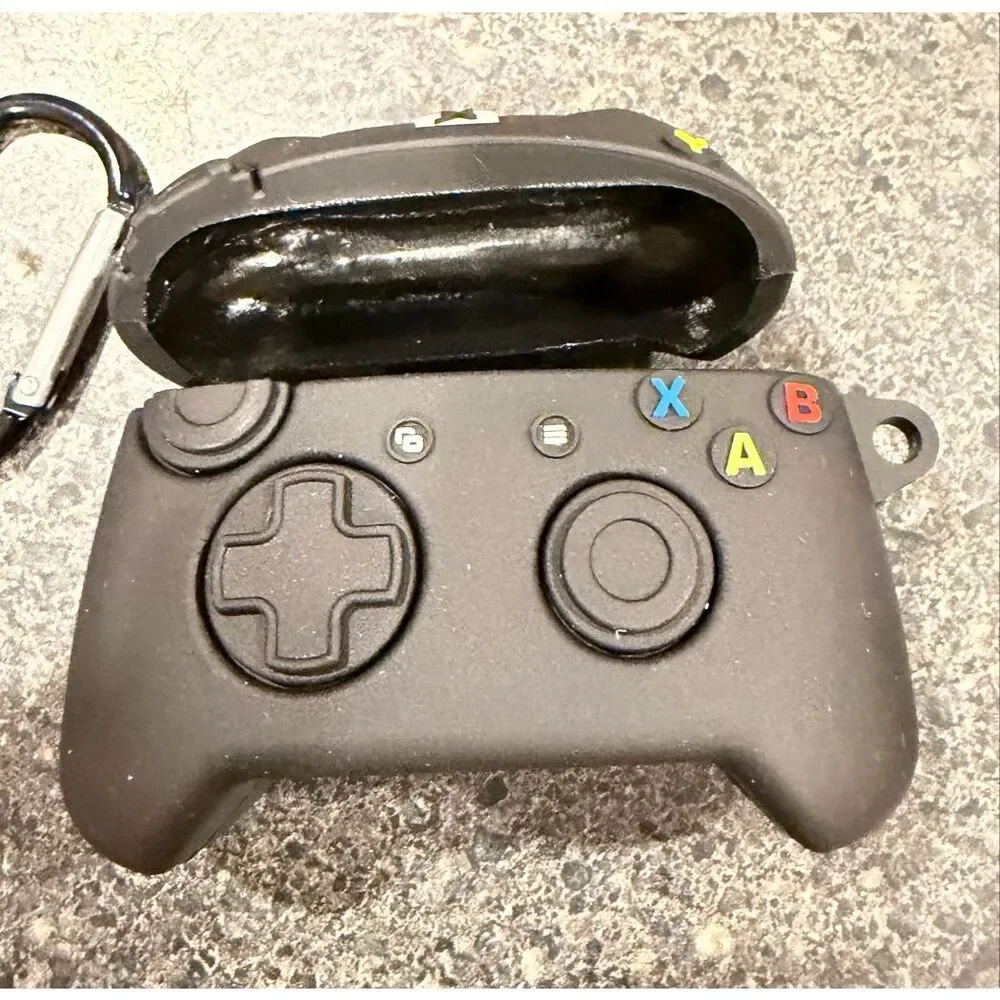 Silicone protective case for Apple AirPods, designed to resemble a black Xbox co